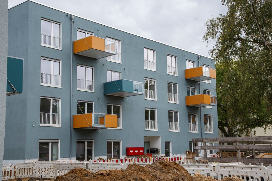 Ein fertiges Wohnhaus mit blauen und orangefarbenen Balkonen.